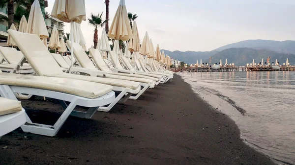 Rijen lege ligbedden en parasols op het strand van de zee bij zonsondergang — Stockfoto
