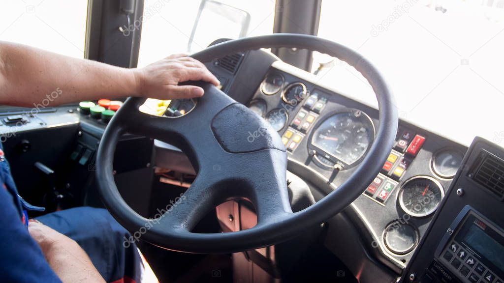 Closeup image of drivers hands on big truck steering wheel
