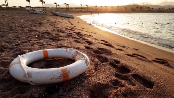 4k footage of calm sea at sunset. Beatiful video of life saving buoy ring and boats on the sea beach — Stock Video