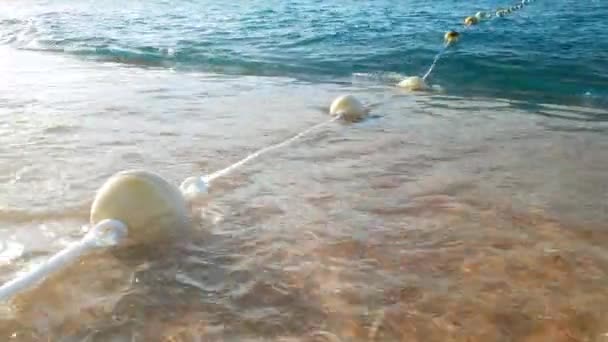 4k primer plano de vídeo de boyas flotantes en la cuerda en calma las olas del mar a la luz del atardecer — Vídeos de Stock