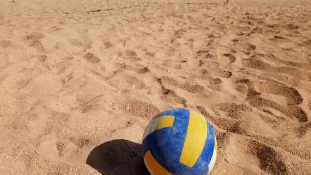 4k metraje de voleibol acostado en la playa de arena en el día ventoso — Vídeo de stock