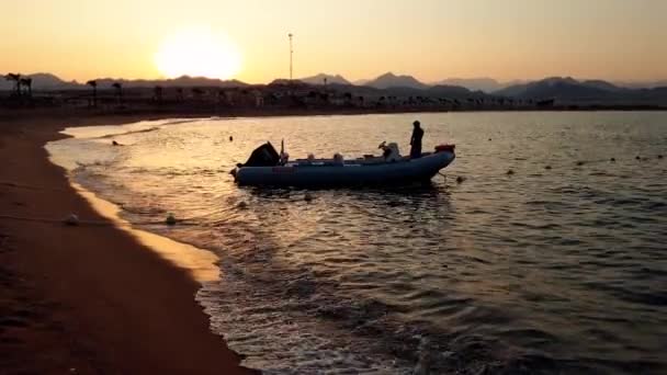 4k Silhouette Video von Schlauchboot mit Motor auf ruhigem Meer Wellen bei Sonnenuntergang — Stockvideo