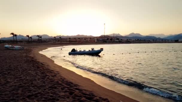 4k Silhouette Video von Schlauchboot mit Motor auf ruhigem Meer Wellen bei Sonnenuntergang — Stockvideo