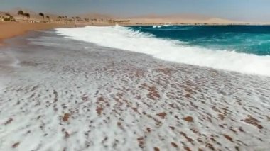 Rüzgarlı güneşli bir günde kumlu plaj üzerinde haddeleme büyük deniz dalgaları 4k video