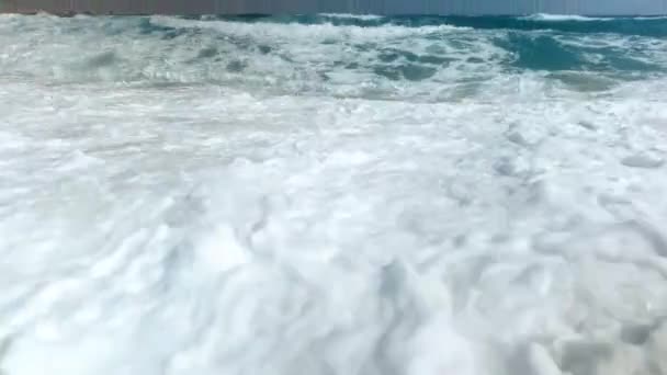 4k video de grandes olas marinas rodando sobre la playa de arena en un día soleado y ventoso — Vídeos de Stock