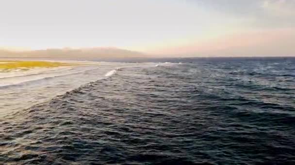 4k video of camera panning over the ocean coastline at sunset — Stock Video