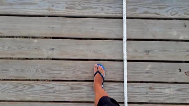 4k footage of male feet in flip flops walking on the wooden walkway on the long pier in the sea — Stock Video