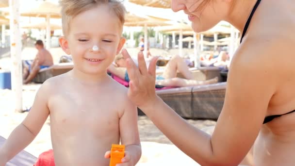 Vídeo 4k de família sorridente feliz aplicando UV loção de proteção solar na praia do mar no dia ensolarado quente — Vídeo de Stock