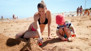 3 yaşındaki küçük oğluyla sahilde oynayan güzel genç annenin 4k yavaş çekim görüntüleri. Denizde dinlenen aile