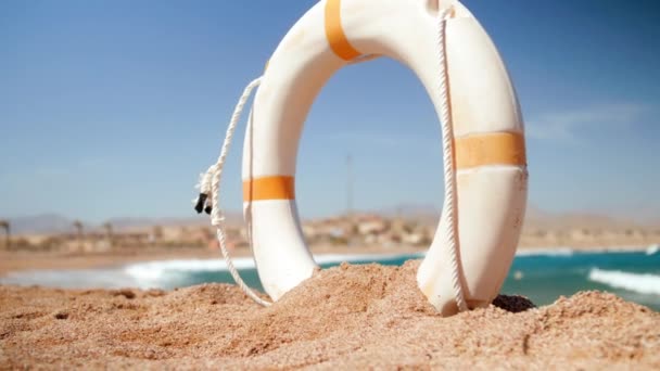 4k belle vidéo au ralenti de la bouée de sauvetage anneau creusé dans le sable sur la plage de la mer — Video