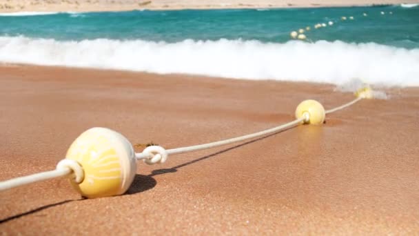 Imágenes en cámara lenta de 4k de olas marinas rodando en la playa del mar y rompiendo boyas flotantes — Vídeos de Stock