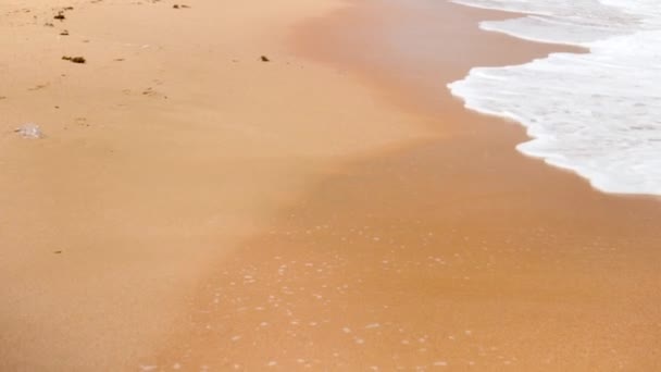 Imágenes en cámara lenta 4k de la cámara volando por encima de romper olas marinas en la playa de arena — Vídeo de stock