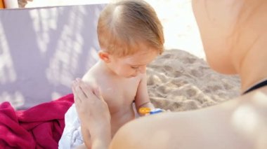 Sıcak güneşli bir günde deniz plajında Uv güneş koruma losyonu uygulayan mutlu gülümseyen ailenin 4k video