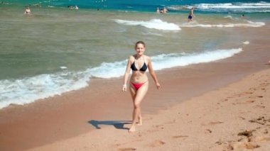 Kumlu plajda denizden çıkan bikinili genç kadının 4k slow motion videosu