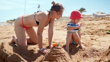 3 yaşındaki oğlu ile deniz sahilinde bikini bina kum kale genç anne 4k görüntüleri
