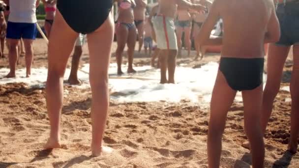 4k cámara lenta fuera de foco video de gente feliz bailando en la playa del mar en día soleado brillante — Vídeos de Stock