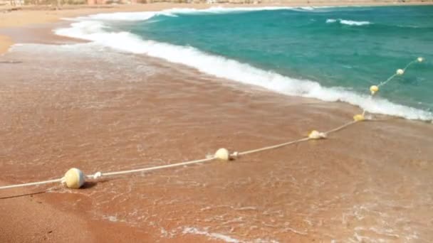 Images au ralenti 4k de vagues de mer roulant sur la plage de la mer et se brisant sur des bouées flottantes — Video