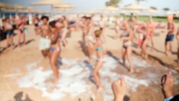 밝은 화창한 날에 디스코에 바다 해변에서 춤추는 군중의 4K 흐릿한 비디오 — 비디오