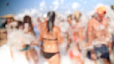 Parlak güneşli bir günde plajda dans mayo ve bikini neşeli kalabalık 4k video. Sabun köpüğü partisi olan gençler