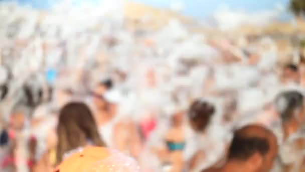 4k cámara lenta fuera de foco metraje de jóvenes alegres felices teniendo fiesta de espuma de jabón en la playa del mar. Multitud bailando y divirtiéndose en vacaciones de verano — Vídeos de Stock