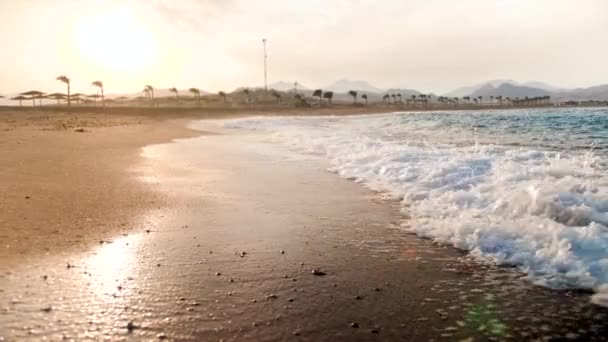 4k schöne Zeitlupenaufnahmen von Meereswellen, die bei Sonnenuntergang am Sandstrand rollen — Stockvideo