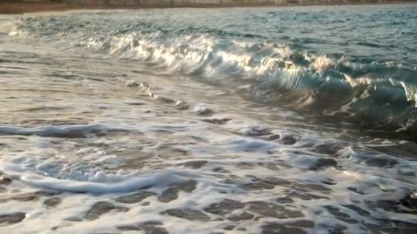 Closeup slow motion video of swirling and boiling sea water after waves crushing on the shore at sunset — Stock Video