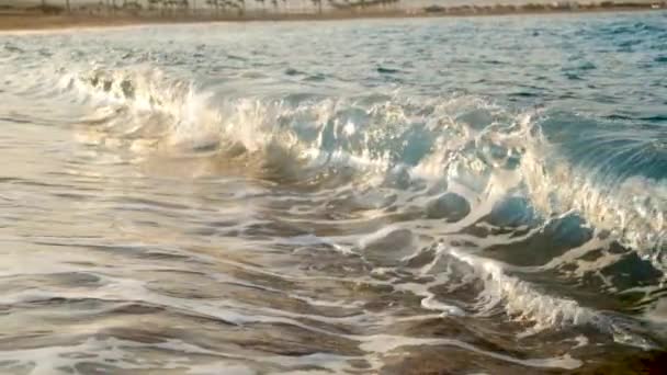 Vídeo em câmera lenta extrema de ondas do mar rolando na praia de areia dourada ao pôr do sol — Vídeo de Stock