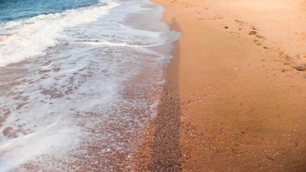 Slow motion synvinkel video av promenader längs havet vågor på gyllene sand — Stockvideo