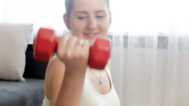 Dambılile evde fitness egzersizleri yapan güzel gülümseyen genç kadın 4k video