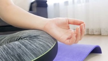 Lotus asana oturan ve meditasyon genç kadın 4k closeup dolly video. Evde yoga yapan kız