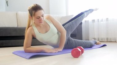Fitness egzersizleri yaptıktan sonra evde yoga minderi üzerinde uzanan genç kadının 4k görüntüleri