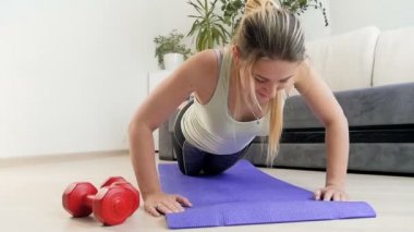 Evde fitness mat üzerinde şınav yaptıktan sonra yere düşen yorgun genç kadının yavaş çekim görüntüleri