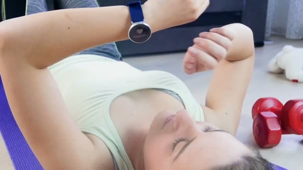 Filmato al rallentatore di una giovane donna che usa un fitness tracker al polso prima di fare esercizi sportivi — Video Stock