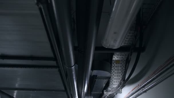 Imágenes de 4k de lámparas industriales y tuberías en el techo de un edificio moderno. Grungy background. Cámara moviéndose a lo largo de interior oscuro en tela — Vídeos de Stock