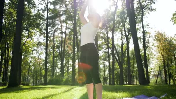 4k lassú mozgás videó gyönyörű mosolygó középkorú nő csinál jóga gyakorlatok és nyújtás a parkban. Ez igazi hasznos részére elmebeli és fizikai egészség. Kikapcsolódás a természetben — Stock videók