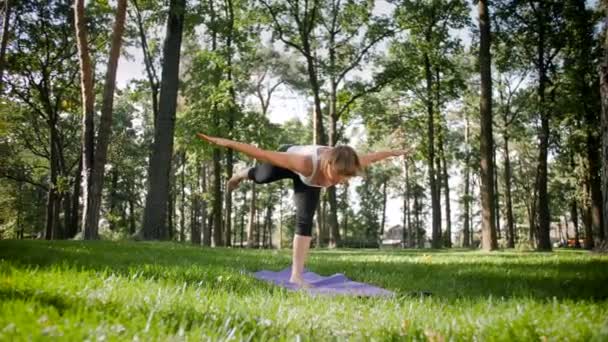 Yoga egzersizleri yapıyor ve parkta germe güzel gülümseyen orta yaşlı kadın 4k yavaş hareket video. Bu zihinsel ve fiziksel sağlık için çok yararlıdır. Doğada dinlenen insanlar — Stok video