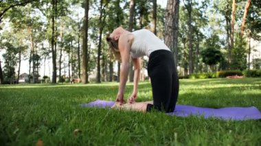 Yoga egzersizleri yapıyor ve parkta germe güzel gülümseyen orta yaşlı kadın 4k yavaş hareket video. Bu zihinsel ve fiziksel sağlık için çok yararlıdır. Doğada dinlenen insanlar