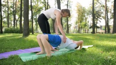 Parkta egzersiz anne ile çocuk yavaş hareket 4k görüntüleri. Aile yoga yapıyor ve doğada germe. Ciddi ve fiziksel bakım. Doğada uyum