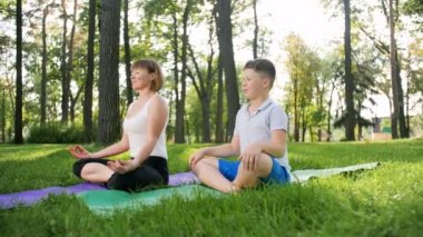 Parkta yoga ve fitness egzersizleri yapan yetişkin kadın ile çocuk 4k video. Ebeveyn öğretim çocuk sağlık bakımı