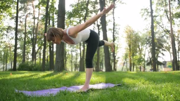 Vidéo au ralenti 4k de belle femme d'âge moyen souriante faisant des exercices de yoga et s'étirant dans le parc. Il est très utile pour la santé mentale et physique. Les gens se relaxent à la nature — Video