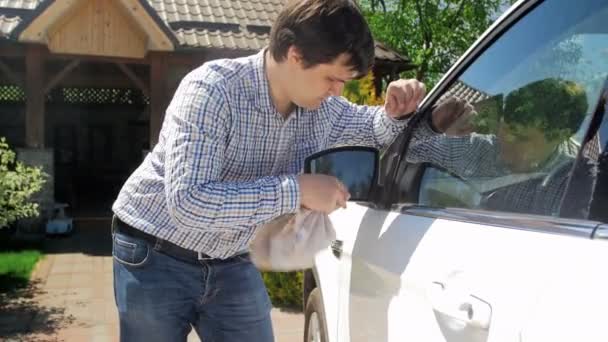 Images 4k montrant un conducteur qui nettoie les vitres et les phares de sa voiture dans la cour arrière de sa maison. Prendre soin de son véhicule personnel — Video