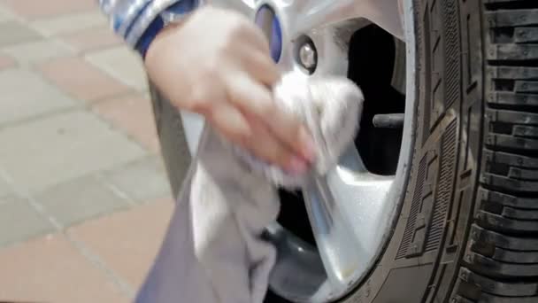 4k видео, где человек чистит и полирует грязные колеса на своей машине на заднем дворе дома — стоковое видео