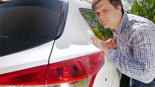 Vidéo au ralenti montrant un jeune homme inspectant sa nouvelle voiture. Conducteur masculin touchant son véhicule à la main — Video