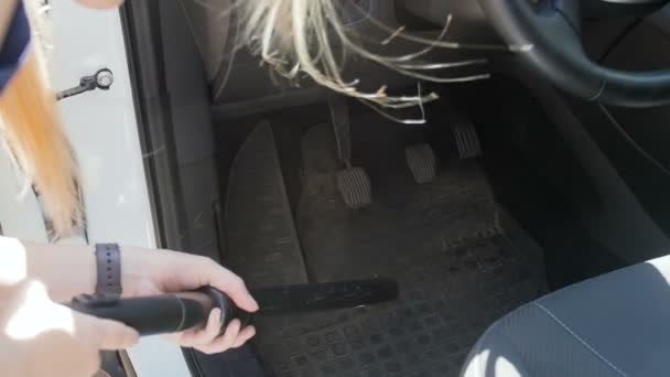 Vídeo em câmera lenta de uma jovem usando o hoover para limpar o interior do carro do pó e da sujeira. Motorista fêmea limpando veículo no quintal da casa — Vídeo de Stock