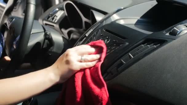 Крупный план замедленного съемки, где молодая женщина чистит приборную панель автомобиля от пыли и грязи с помощью микроволоконной ткани. Полировка водителя пластика в салоне автомобиля — стоковое видео