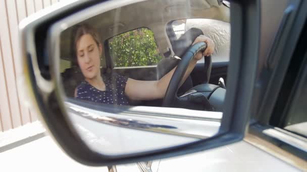 Медленное видео движения молодой женщины-водителя, регулирующей боковые зеркала перед вождением автомобиля — стоковое видео