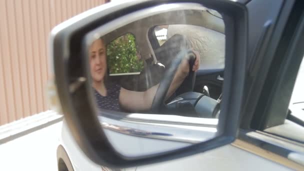 Zbliżenie powolny ruch wideo pięknej uśmiechniętej kobiety dostosowując lusterka samochodowe przed jazdą — Wideo stockowe