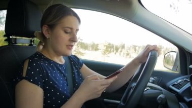 Sorumsuz ve dikkatsiz bir kadının araba kullanırken akıllı telefona mesaj yazarak yavaş çekim videosu. Güvenliğiniz için lütfen araçta handsfree kullanın