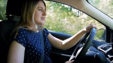 Bir araba sürüş ve radyo ile şarkı güzel genç kadın yavaş hareket video. Bir araba üzerinde seyahat ederken iyi bir ruh hali