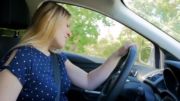 Zeitlupenvideo einer fröhlichen jungen Frau, die singt und tanzt, während sie ein Auto auf der Landstraße fährt — Stockvideo